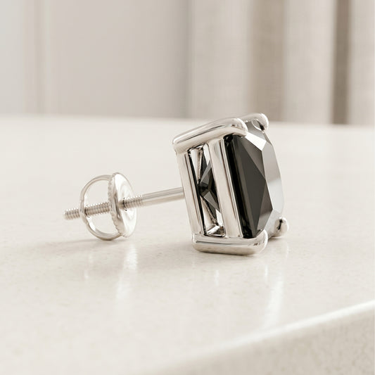 Silver earring with a black gemstone on a light surface