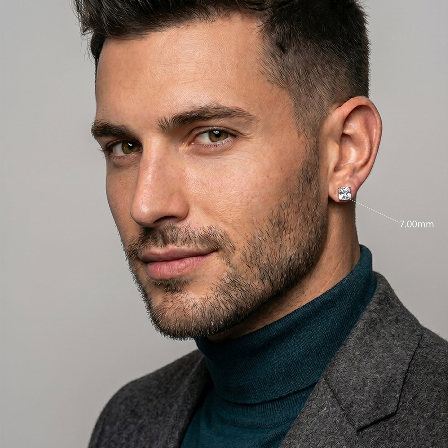 Man wearing a gray coat and teal turtleneck against a neutral background