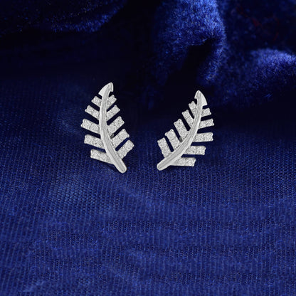 Pair of leaf-shaped earrings on a blue textured fabric background