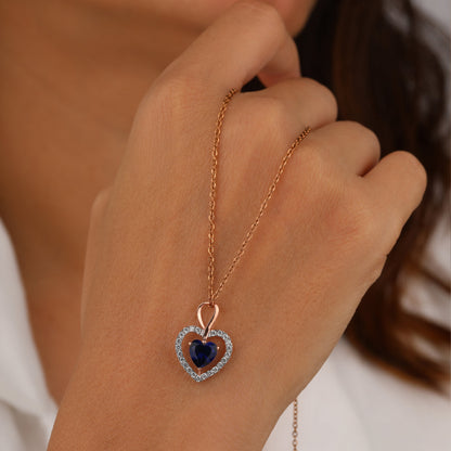 Rose gold necklace with a heart-shaped pendant featuring a blue gemstone 