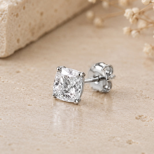 Diamond stud earring on a beige surface with dried flowers