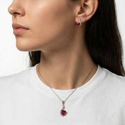 Close-up of a woman wearing a silver necklace with a red pendant