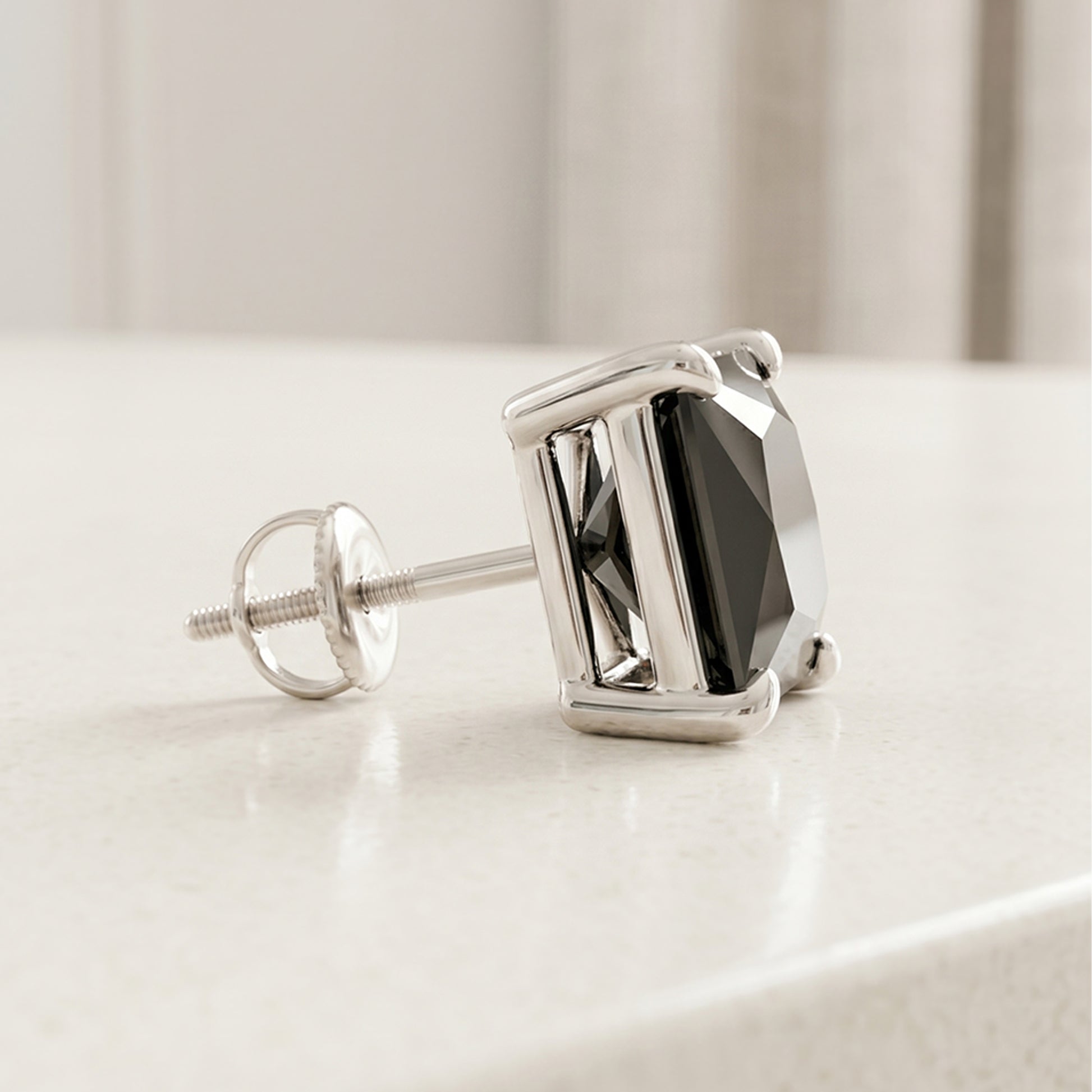 Silver earring with a black gemstone on a light surface