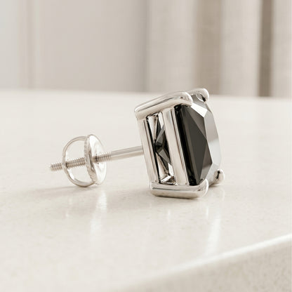 Silver earring with a black gemstone on a light surface