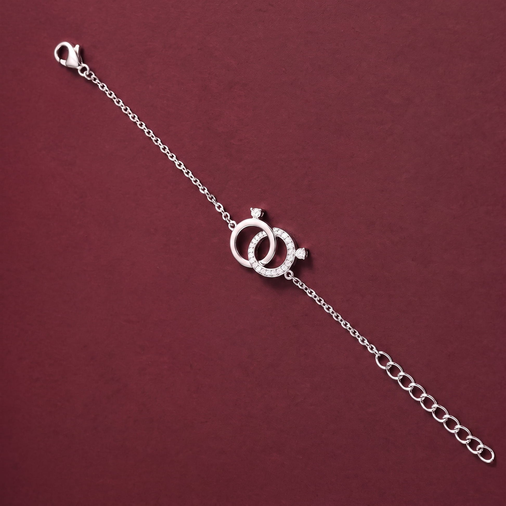 A silver chain bracelet featuring two interlocking rings with small clear stones