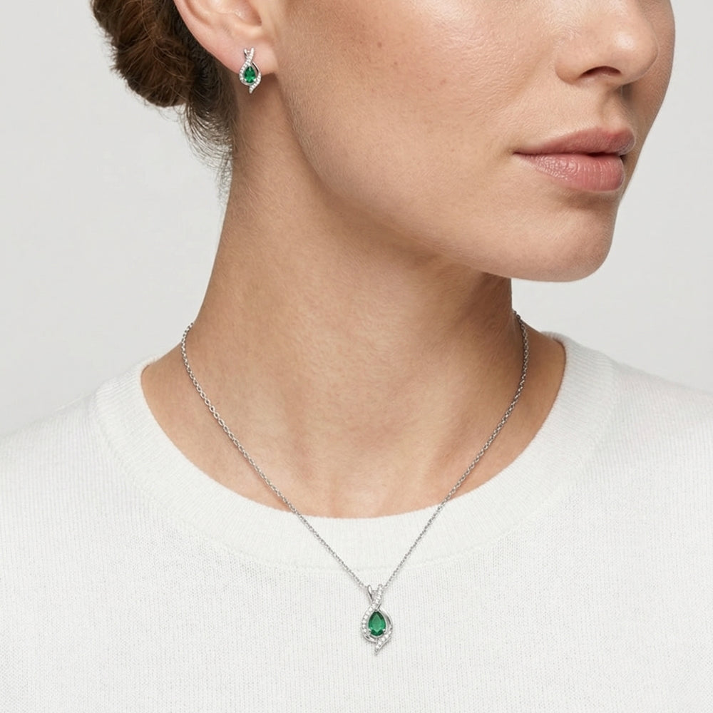 Close-up of a woman wearing a silver necklace with a green pendant and matching earrings.