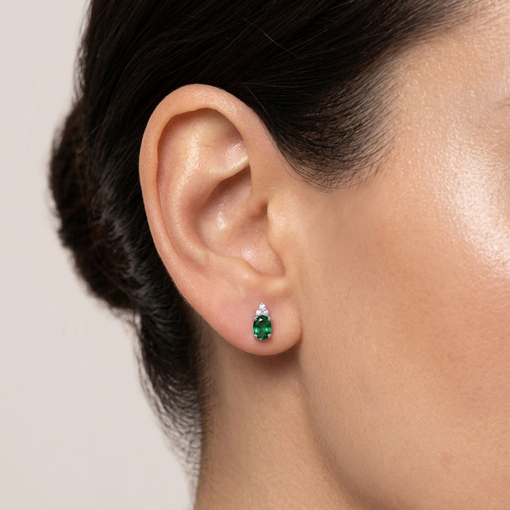 Close-up of an ear wearing a green emerald earring 