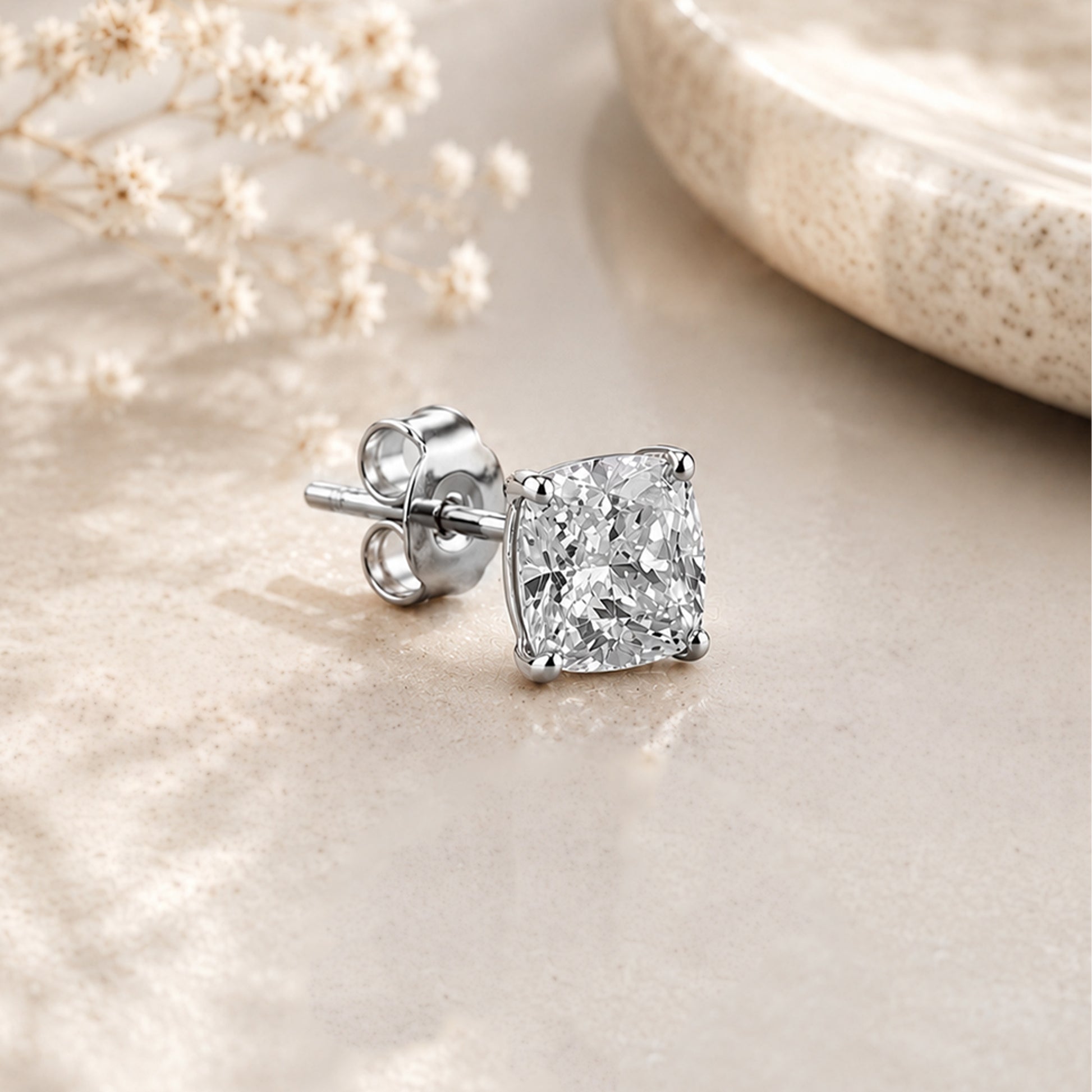 Diamond earring on a textured surface with a soft focus background