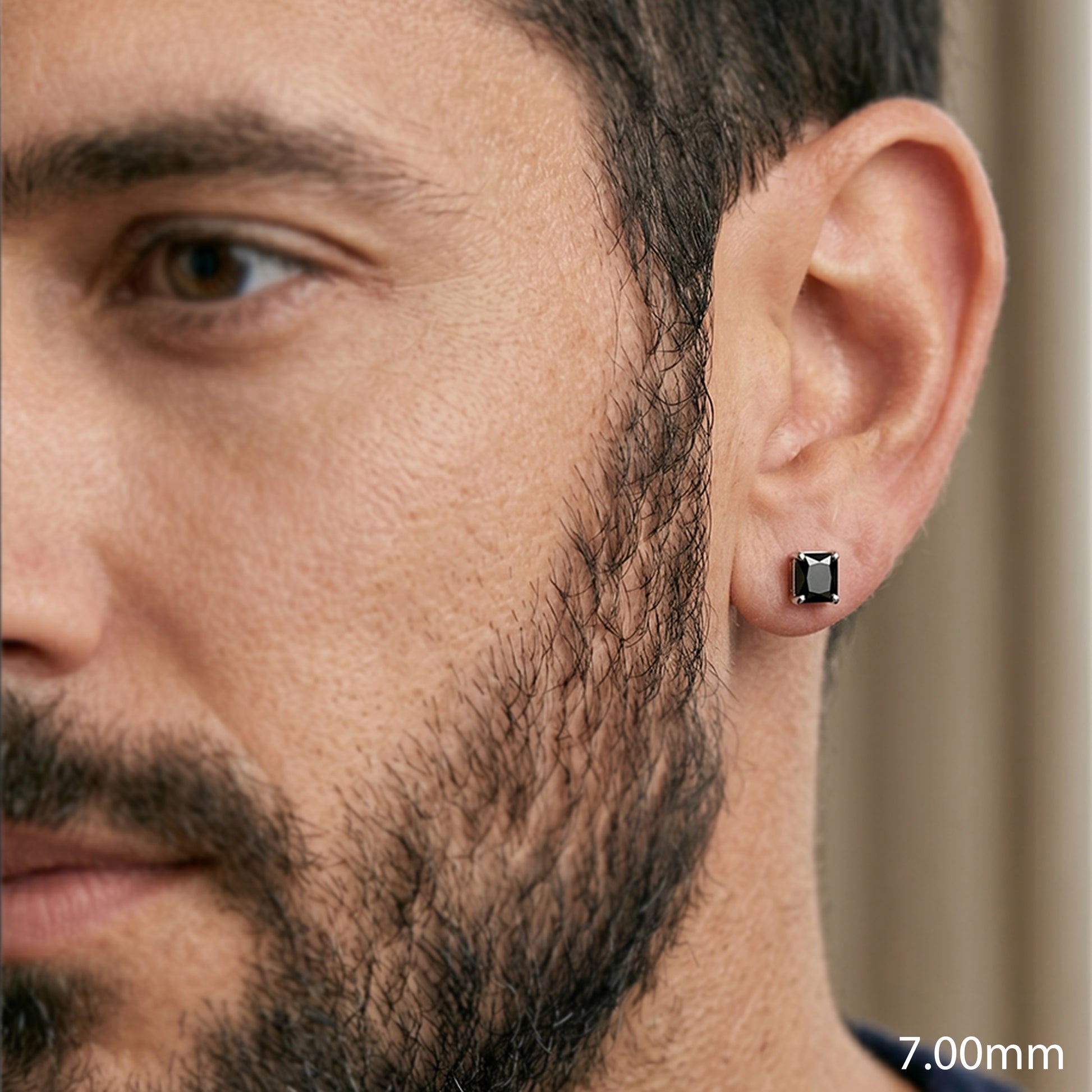 Close-up of a man wearing a black square stud earring.