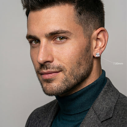 Man wearing a gray coat and teal turtleneck against a neutral background