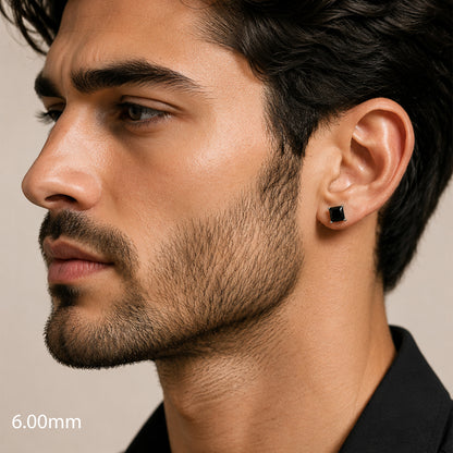 Close-up of a man wearing a black earring on a neutral background