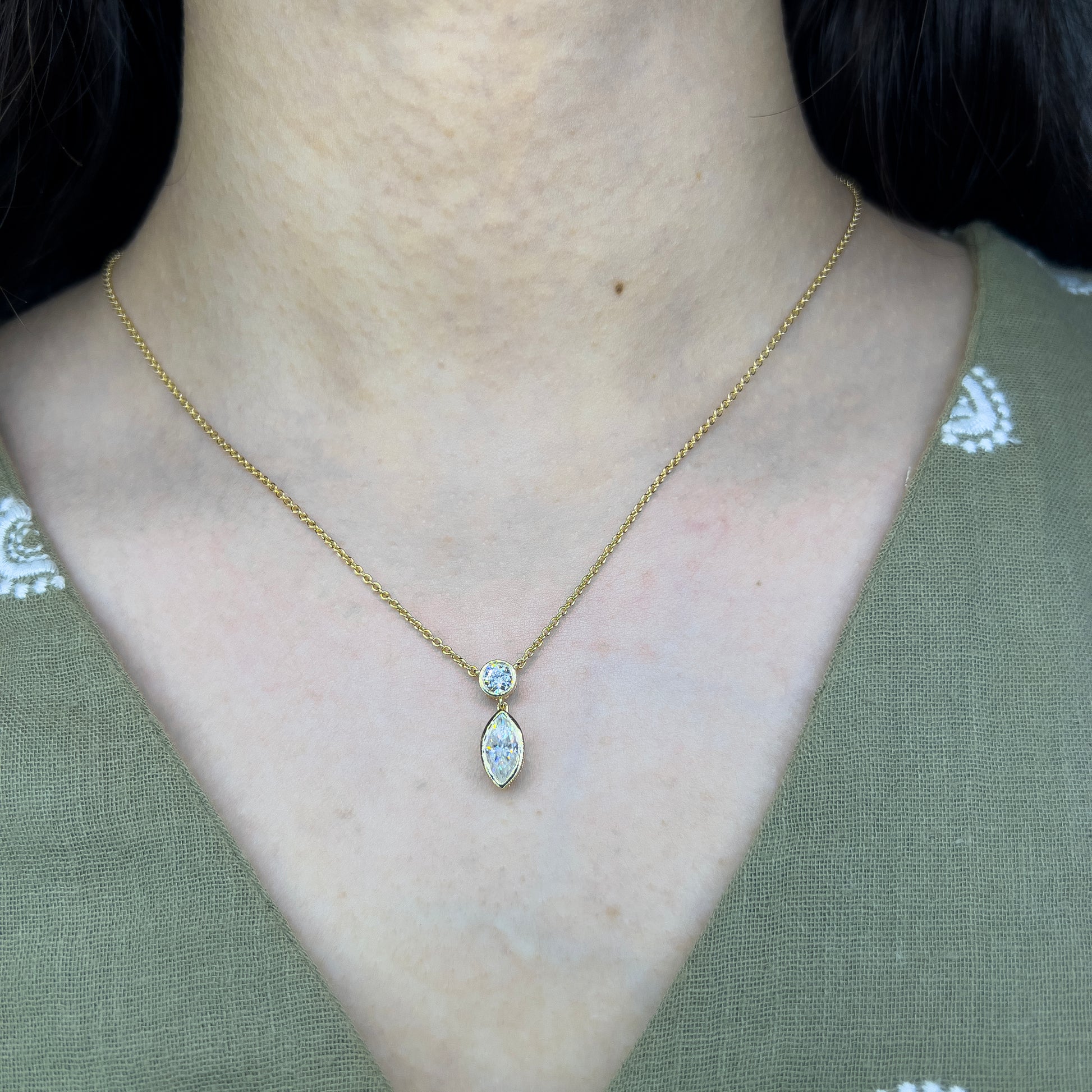 Gold necklace with a pendant worn by a person against a green background
