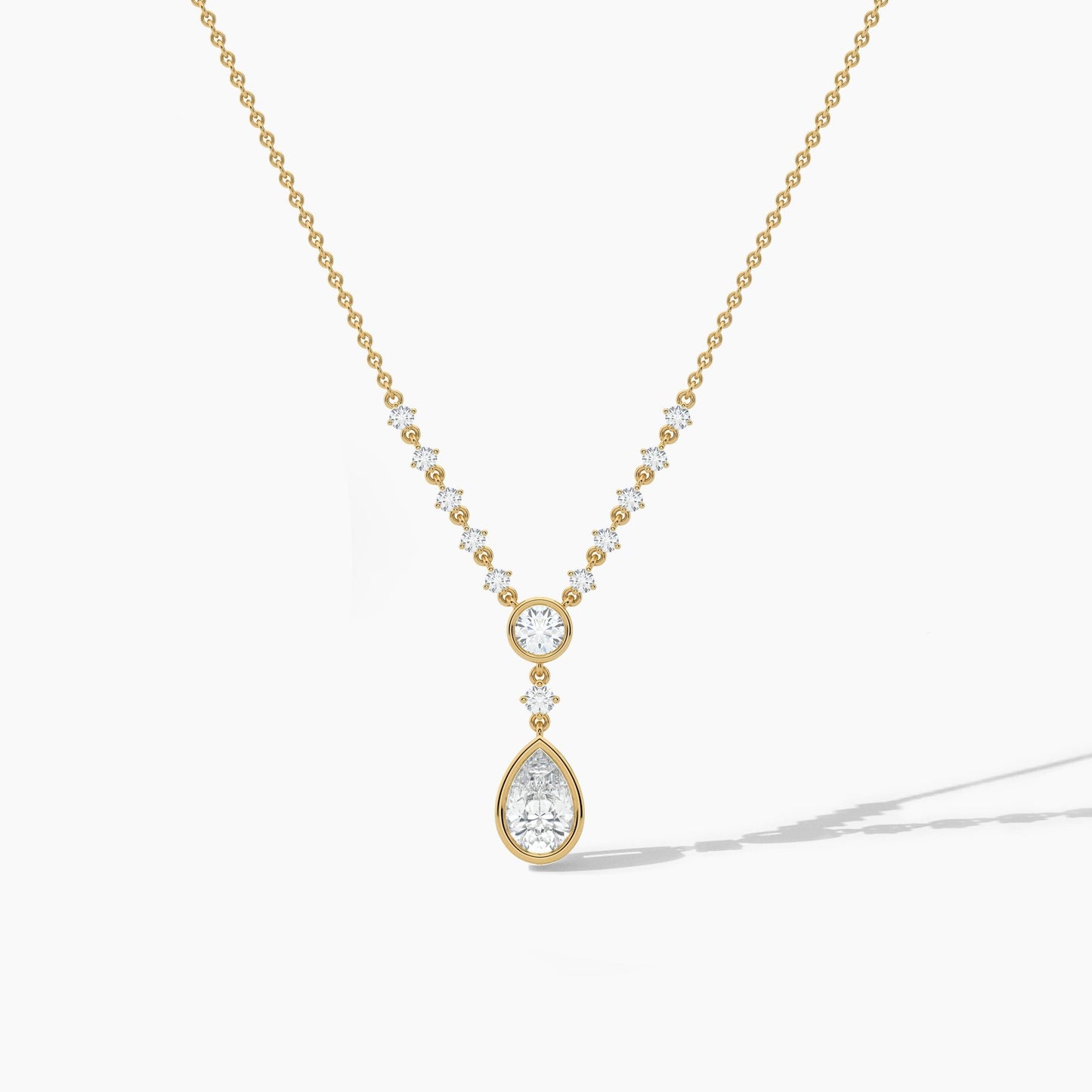 Gold necklace with a teardrop-shaped pendant on a white background