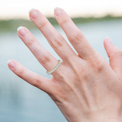Hand wearing a diamond ring with a blurred natural background