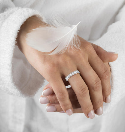 Hand wearing a silver ring with a feather on a white background