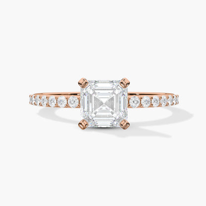 Rose gold ring with a large diamond and smaller diamonds on the band against a white background